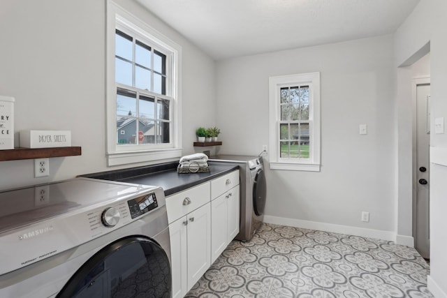 laundry area featuring baseboards, cabinet space, and washing machine and clothes dryer