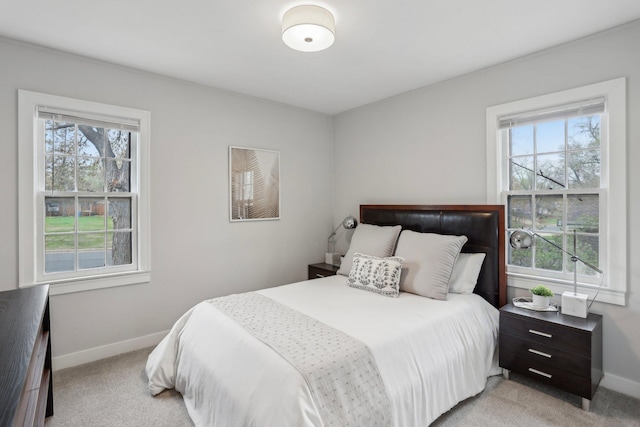 bedroom featuring baseboards, light colored carpet, and multiple windows