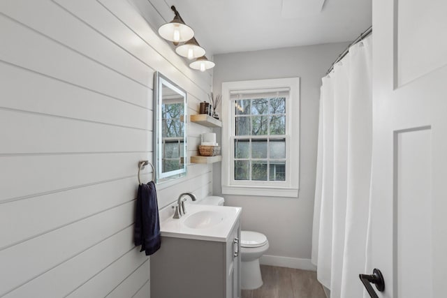 bathroom with baseboards, wood finished floors, toilet, and vanity