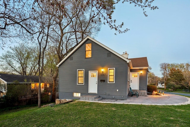 rear view of house with a lawn, a chimney, and a patio area