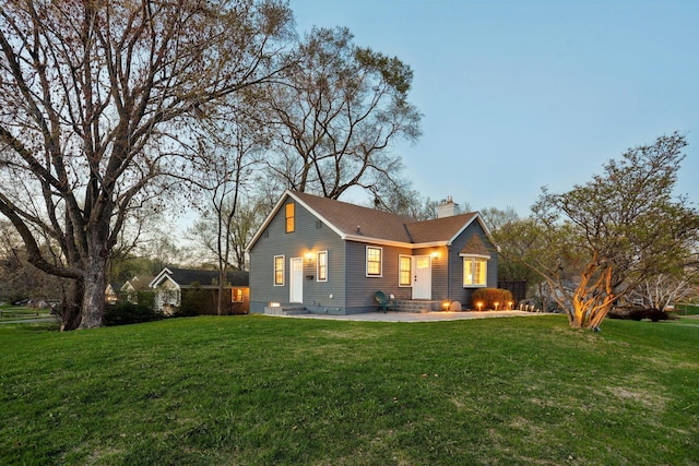back of house featuring a yard, a chimney, and a patio area