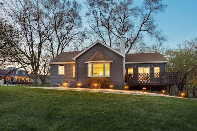 back of property featuring a lawn, a shingled roof, a chimney, and a deck