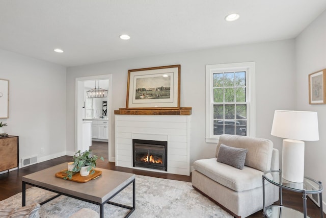 living room featuring visible vents, recessed lighting, a glass covered fireplace, and wood finished floors