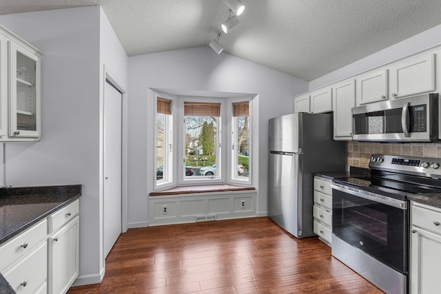 kitchen with lofted ceiling, visible vents, decorative backsplash, appliances with stainless steel finishes, and dark wood-style flooring