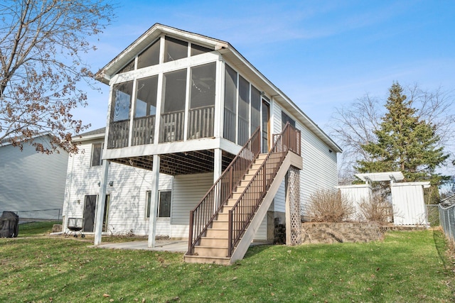 back of property featuring a sunroom, stairs, fence, and a lawn