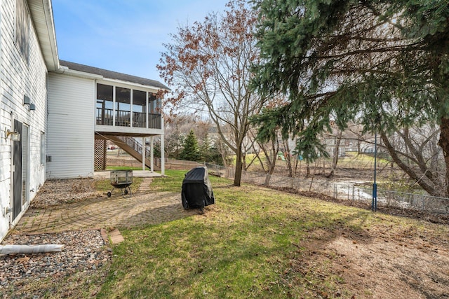 view of yard featuring stairway, a patio area, a fenced backyard, and a sunroom