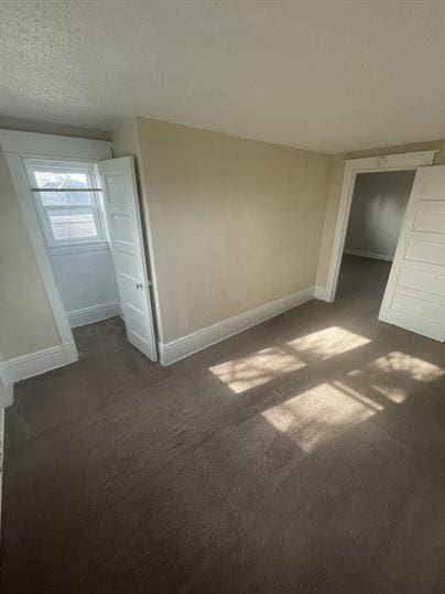 unfurnished bedroom with baseboards and dark colored carpet