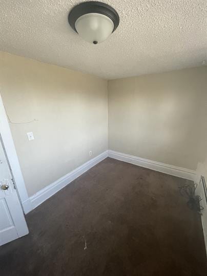 empty room with a textured ceiling and baseboards