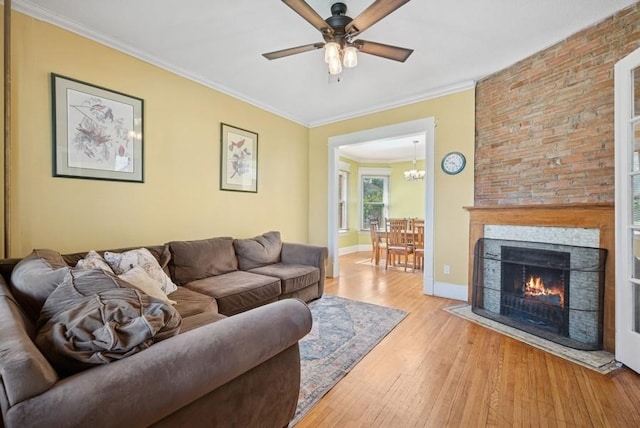 742 Laurel Ave, Saint Paul, MN 55104 - living room with light wood-type flooring, a ceiling fan, crown molding, a large fireplace, and a chandelier