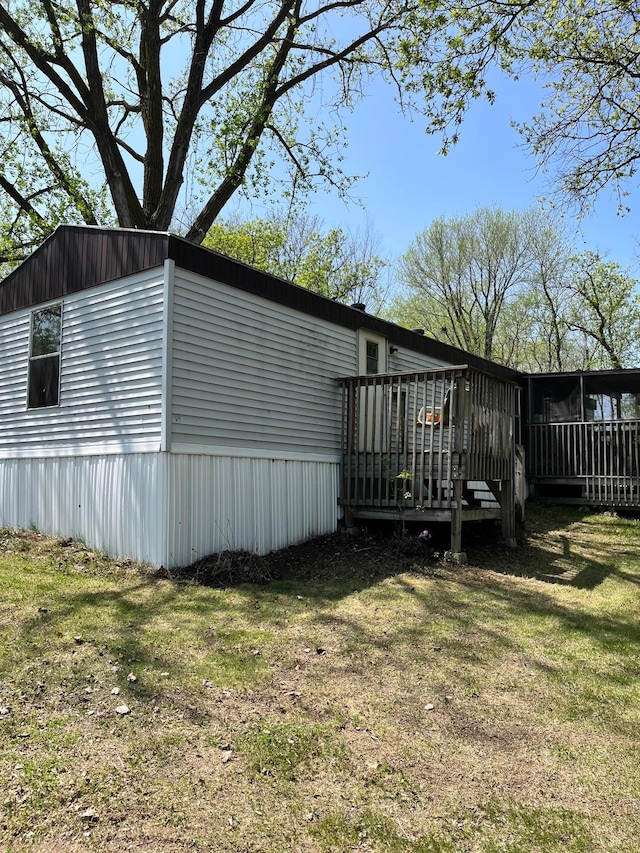 view of side of home featuring a lawn and a deck