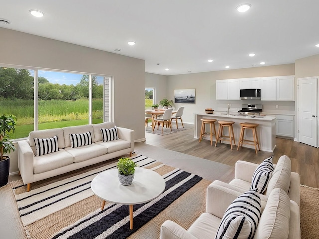 living area with light wood finished floors, recessed lighting, and baseboards