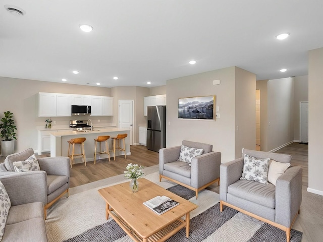 living area with recessed lighting, light wood-style floors, and baseboards