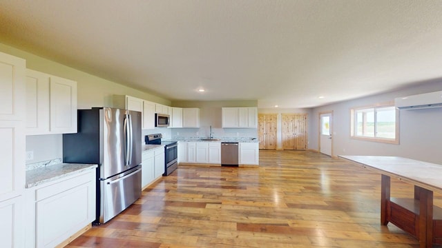1950 228th Ln W, Mora, MN 55051 - kitchen with stainless steel appliances, a wall mounted air conditioner, light wood-style flooring, white cabinetry, and recessed lighting