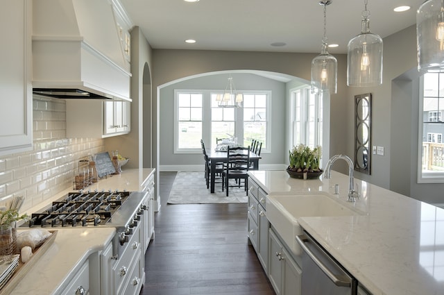 kitchen featuring stainless steel appliances, a sink, arched walkways, recessed lighting, and dark wood-type flooring