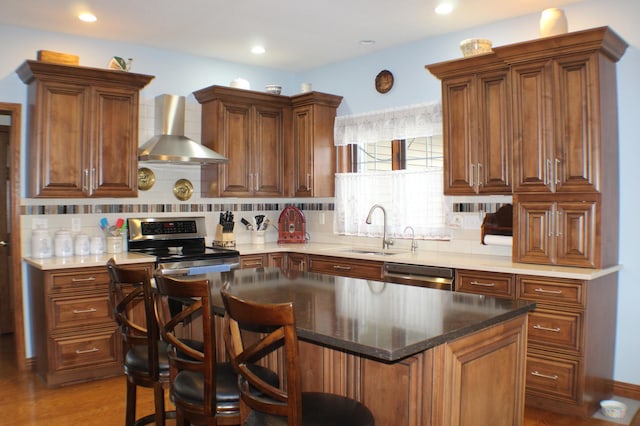 kitchen featuring wall chimney range hood, stainless steel appliances, a sink, and tasteful backsplash