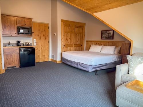 bedroom featuring lofted ceiling, a sink, dark carpet, and wood ceiling