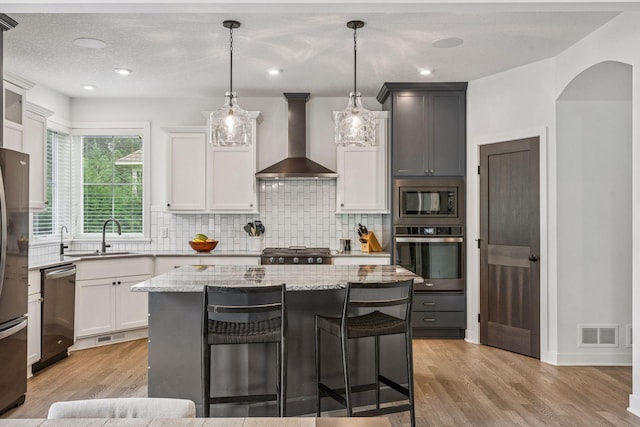 4528 Fable Hill Pkwy N, Hugo, MN 55038 - kitchen with appliances with stainless steel finishes, wall chimney range hood, a sink, light wood finished floors, and light stone counters