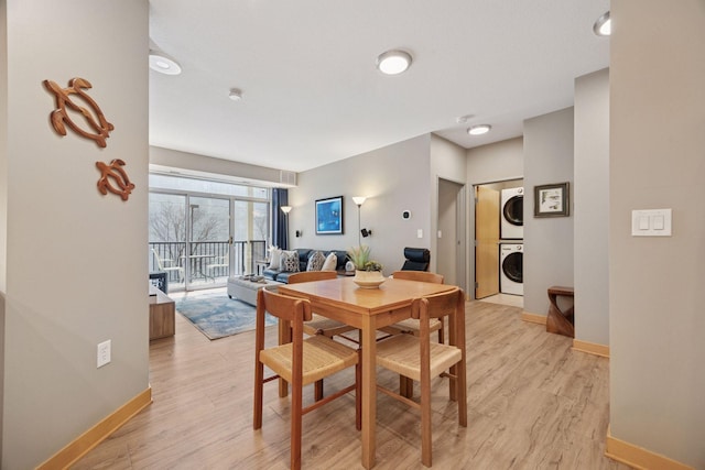 dining space with baseboards, stacked washer and dryer, and light wood finished floors