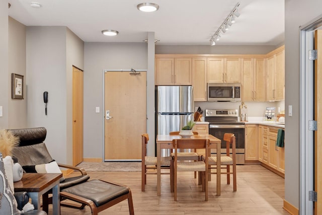 kitchen featuring track lighting, light brown cabinets, light wood-style floors, and appliances with stainless steel finishes