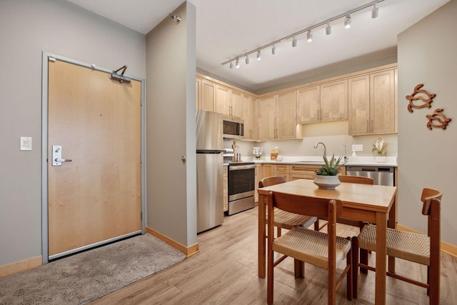 kitchen with light brown cabinets, rail lighting, appliances with stainless steel finishes, and a sink