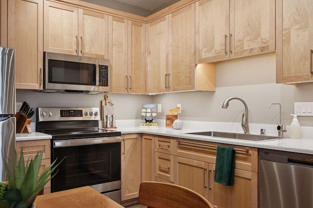 kitchen with appliances with stainless steel finishes, light countertops, light brown cabinetry, and a sink