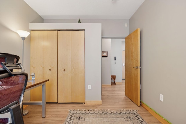 exercise area with baseboards and light wood-style flooring