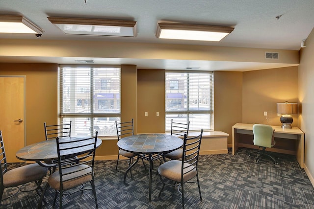 dining space featuring dark colored carpet, visible vents, and baseboards
