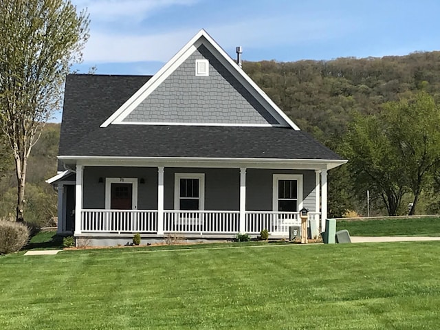 view of front facade featuring covered porch, a shingled roof, and a front lawn