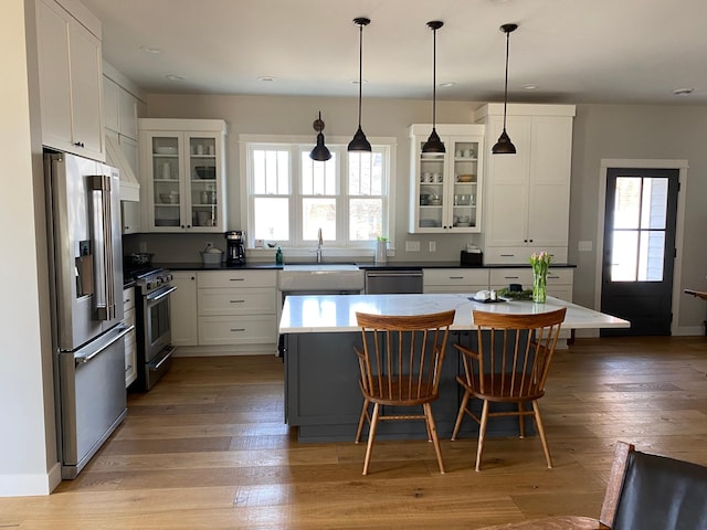 kitchen featuring a sink, high end appliances, a center island, a breakfast bar, and white cabinetry