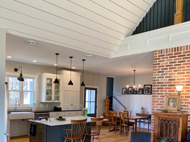 kitchen with an inviting chandelier, glass insert cabinets, light wood-type flooring, a center island, and white cabinets