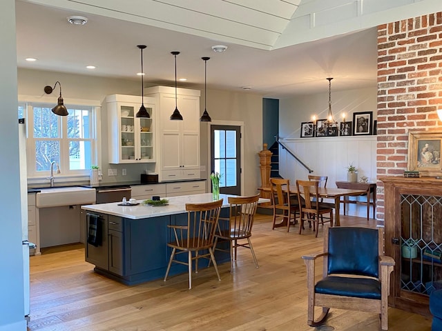 kitchen featuring white cabinetry, light wood-type flooring, dishwasher, and a sink