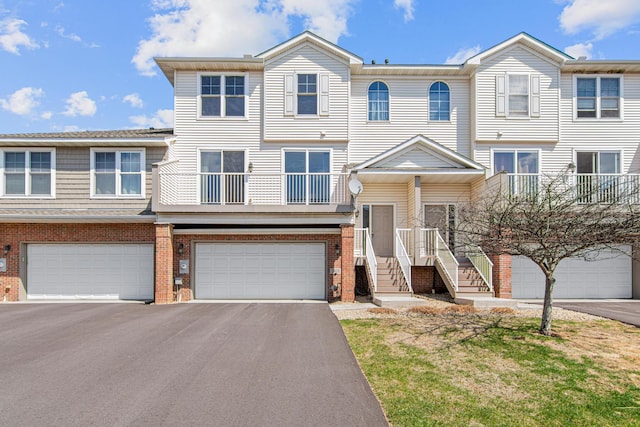 view of property featuring an attached garage, driveway, and brick siding