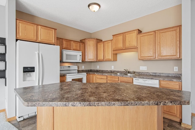 kitchen with dark countertops, baseboards, a sink, and white appliances