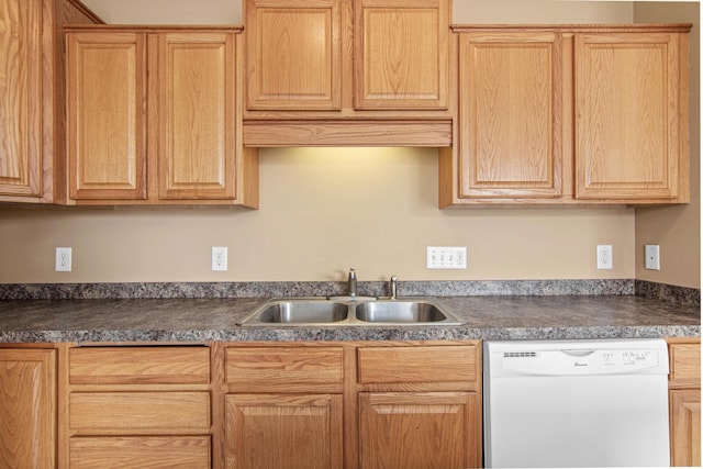 kitchen with dark countertops, white dishwasher, and a sink