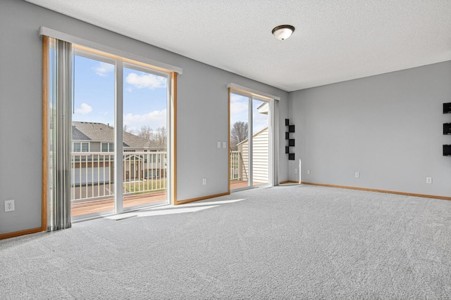 carpeted spare room featuring baseboards and a textured ceiling