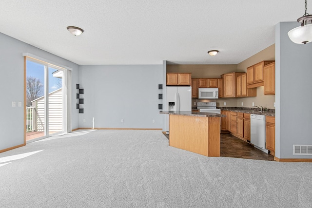 kitchen with visible vents, baseboards, white appliances, and a kitchen island
