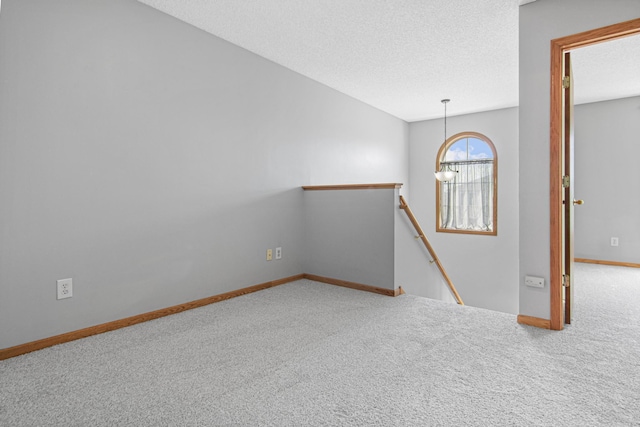 empty room with a notable chandelier, baseboards, carpet floors, and a textured ceiling