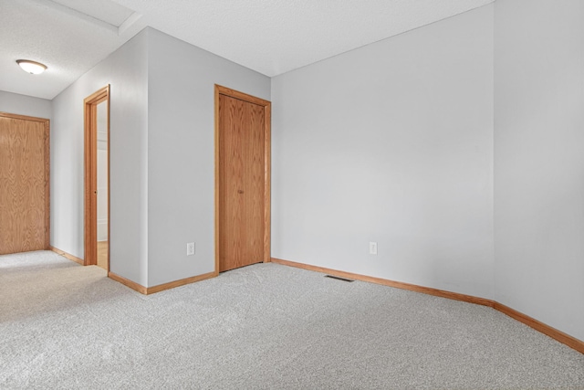unfurnished room featuring attic access, baseboards, and carpet floors