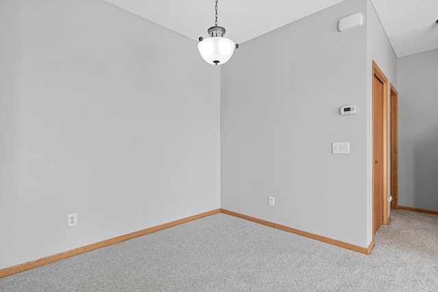 unfurnished dining area featuring carpet floors, a textured ceiling, and baseboards