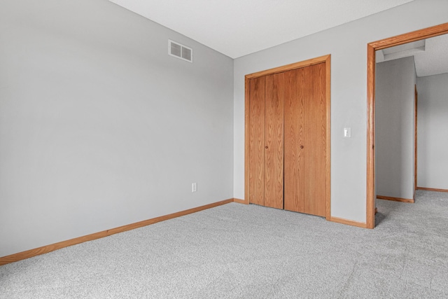unfurnished bedroom featuring baseboards, a closet, visible vents, and carpet