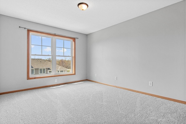 carpeted spare room featuring baseboards