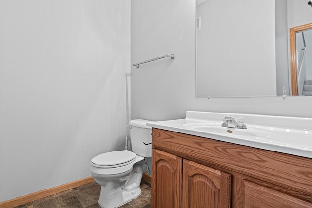 bathroom with baseboards, toilet, and vanity