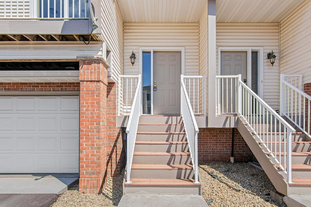 entrance to property featuring an attached garage and brick siding