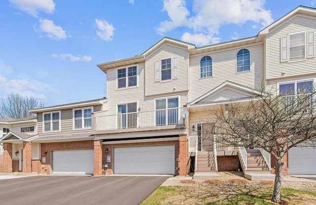 view of property with aphalt driveway, brick siding, and a garage