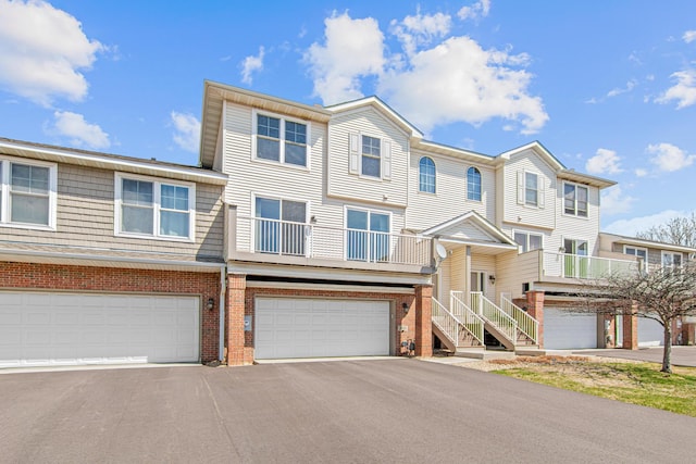 townhome / multi-family property with driveway, brick siding, and a garage
