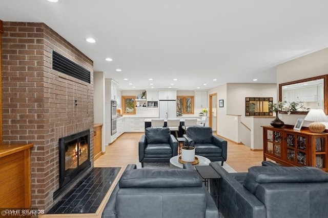 living area featuring a fireplace, light wood-type flooring, and recessed lighting