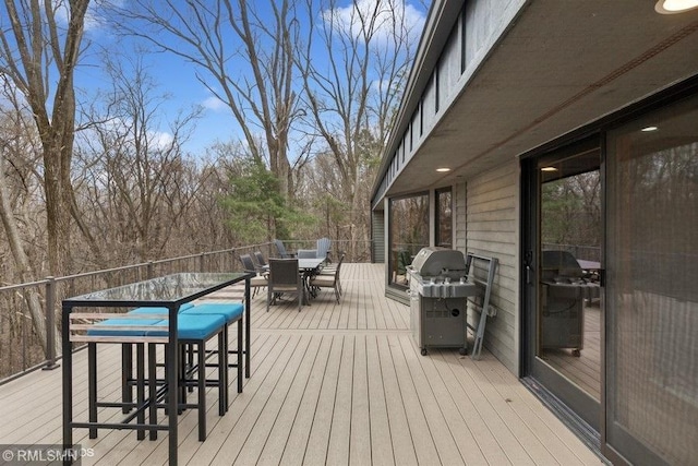 wooden terrace featuring outdoor dining area and a grill