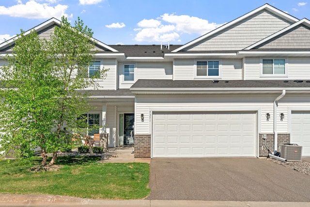 7371 Kalland Cir NE, Otsego, MN 55301 - townhome / multi-family property featuring central AC unit, driveway, brick siding, and a garage