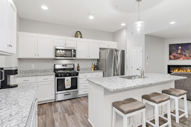 7371 Kalland Cir NE, Otsego, MN 55301 - kitchen featuring appliances with stainless steel finishes, a sink, white cabinets, a kitchen breakfast bar, and light wood-style floors