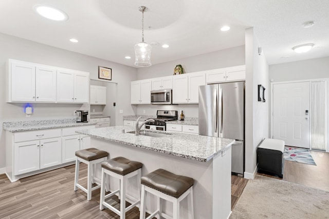 7371 Kalland Cir NE, Otsego, MN 55301 - kitchen with stainless steel appliances, light wood-style flooring, a sink, a breakfast bar area, and white cabinets